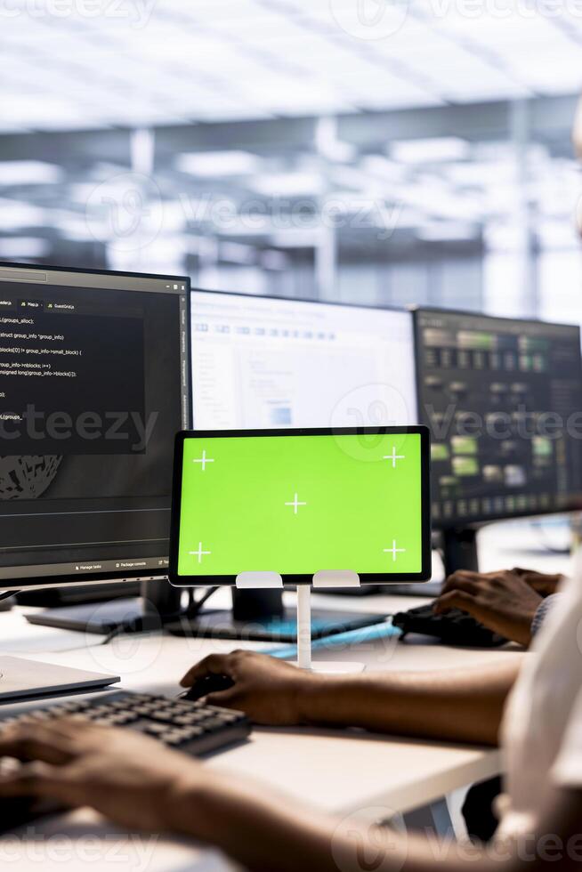 System administrator in server hub ensuring data remains shielded from potential threats using mockup tablet. African american worker safeguarding data center against hackers with green screen device photo