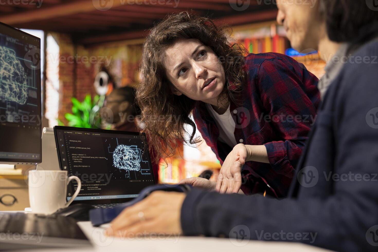 Programmer coming to AI startup office CTO manager desk to request help with building application. Employee asks questions to senior team leader in artificial intelligence software development agency photo