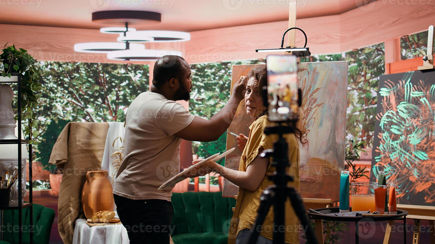 Artists recording creative process of painting an artwork piece, hosting online art class for instruction and remote learning. Diverse painters showing supplies and paint tubes used. Camera b. photo