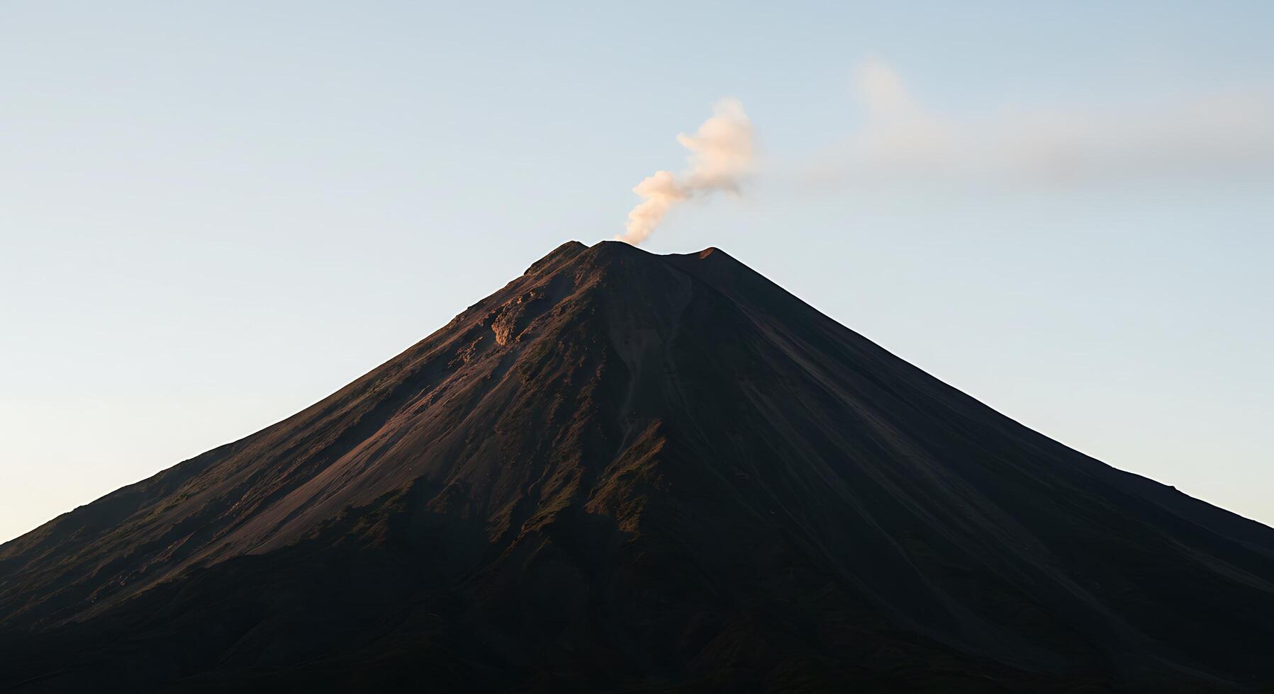 A volcano is seen from above with smoke coming out photo
