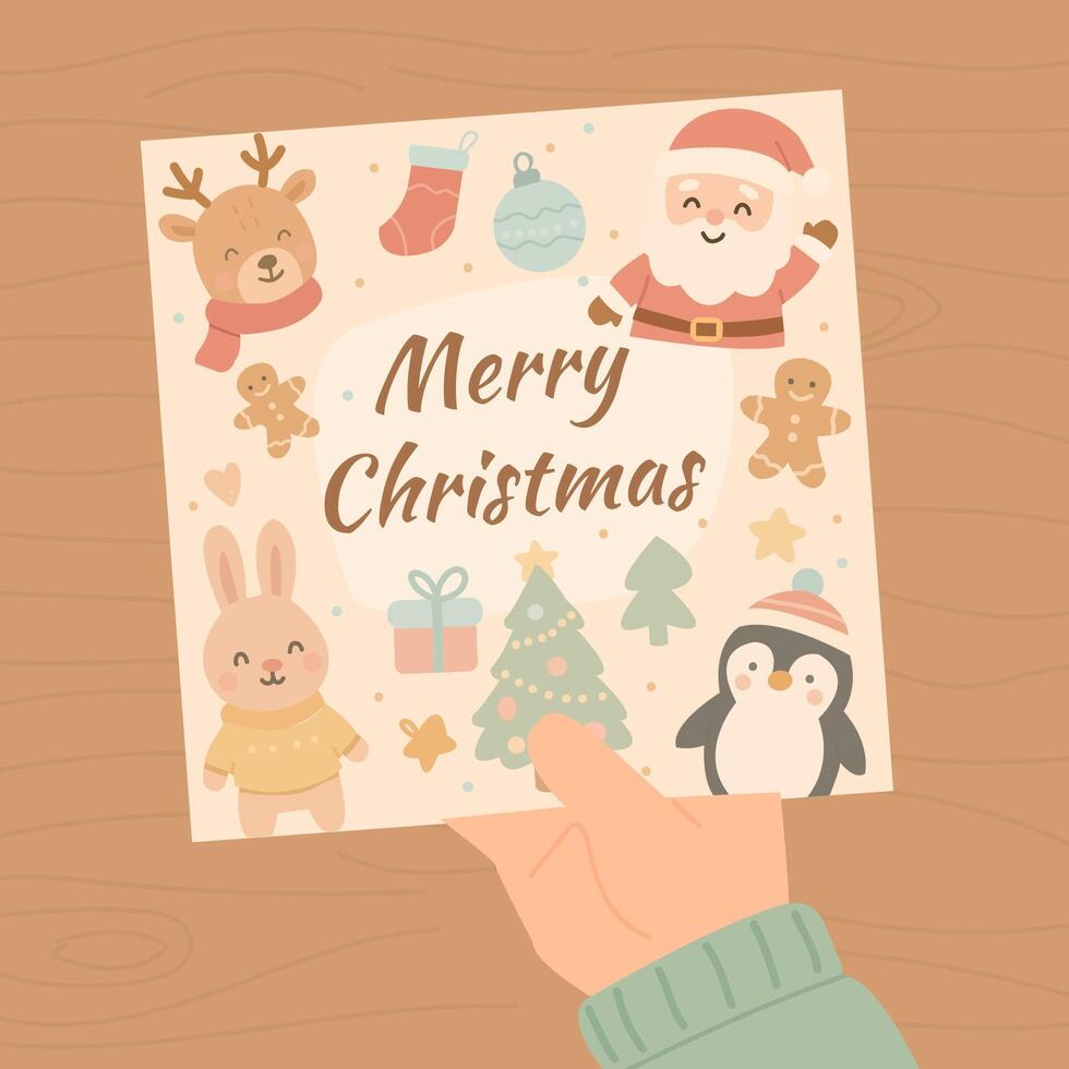 Hand holding cute pastel Merry Christmas card with Santa, bunny, penguin, reindeer, gingerbread cookie and Christmas tree on wooden table background in kawaii cartoon style vector