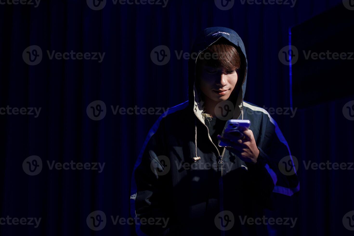 Young man hacker using smartphone for phishing attack and data theft in dark cyber environment photo