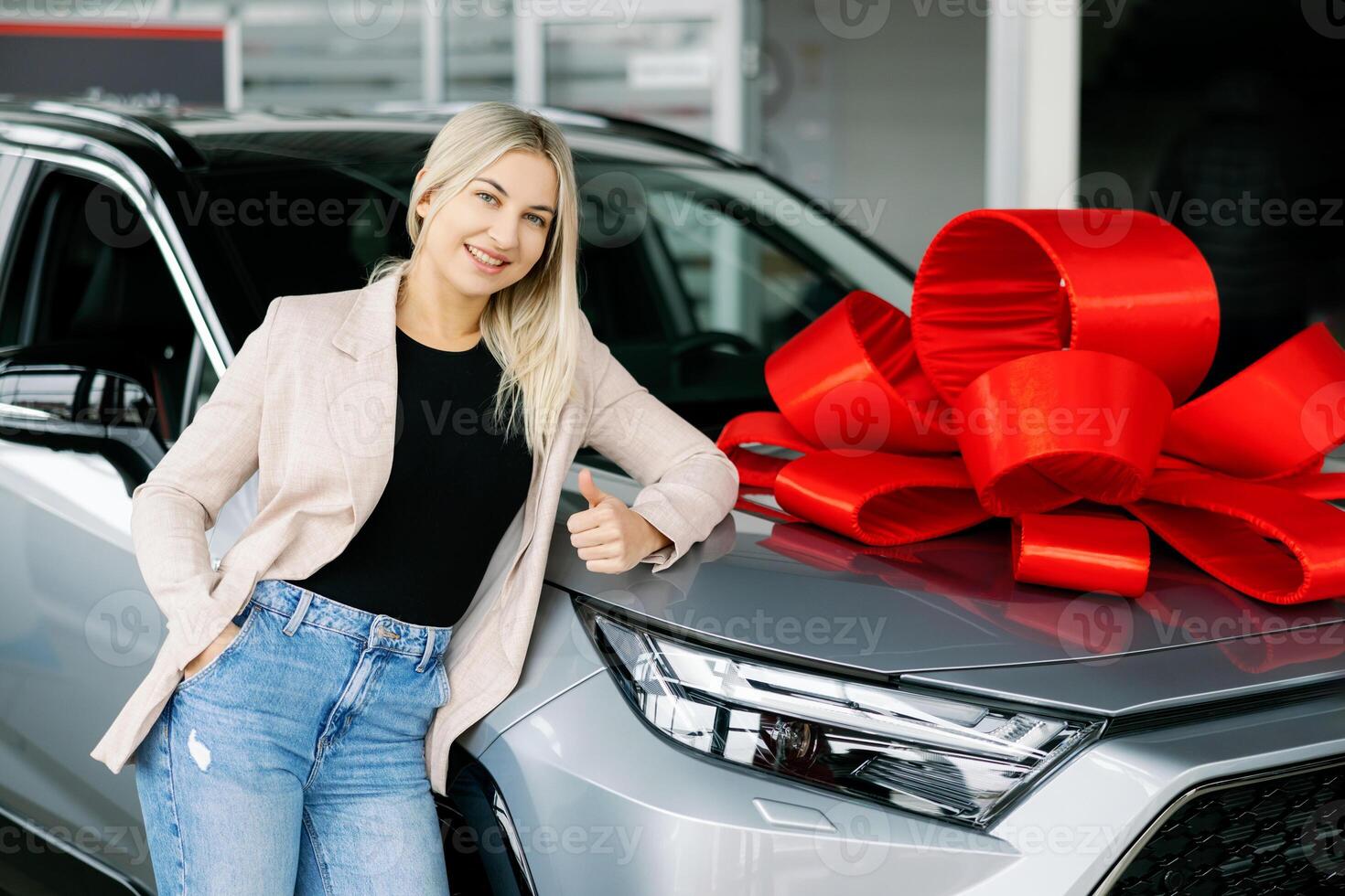 Saleswoman Leaning on New Car with Red Bow in Dealership photo