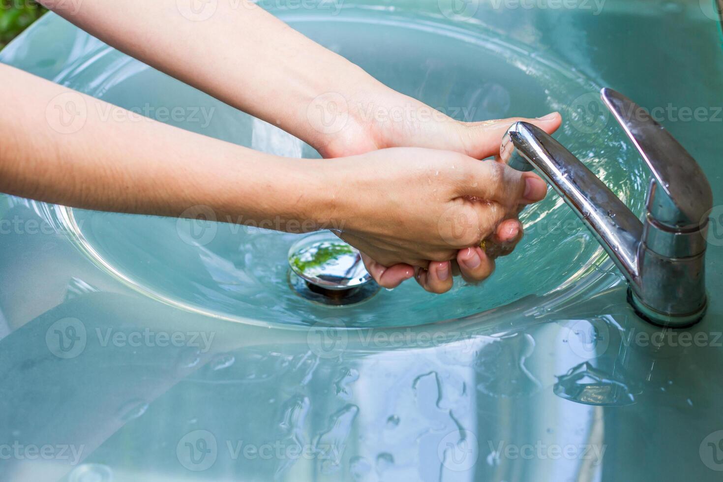 A person washing their hands in a sink photo