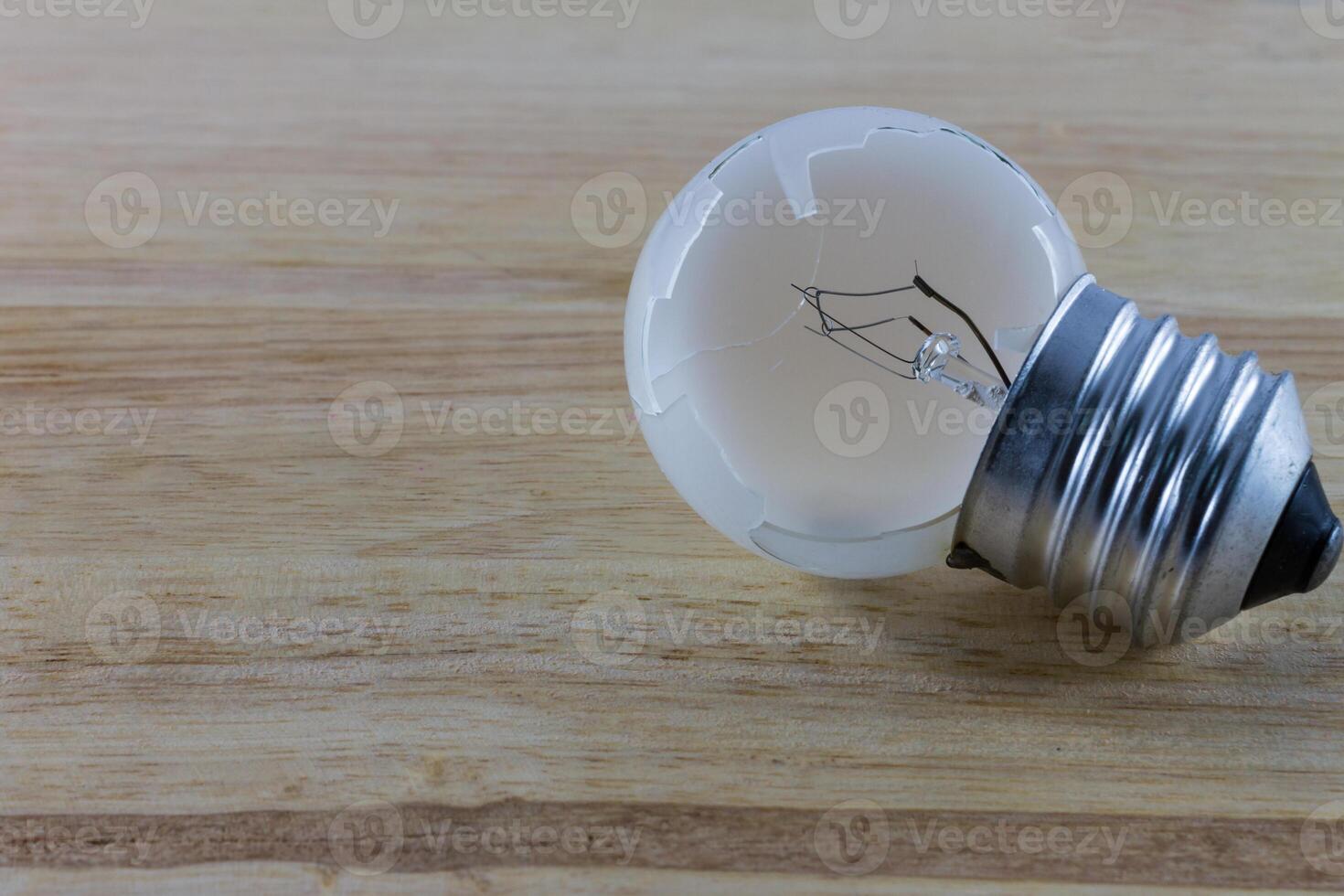 A broken light bulb on a wooden table photo