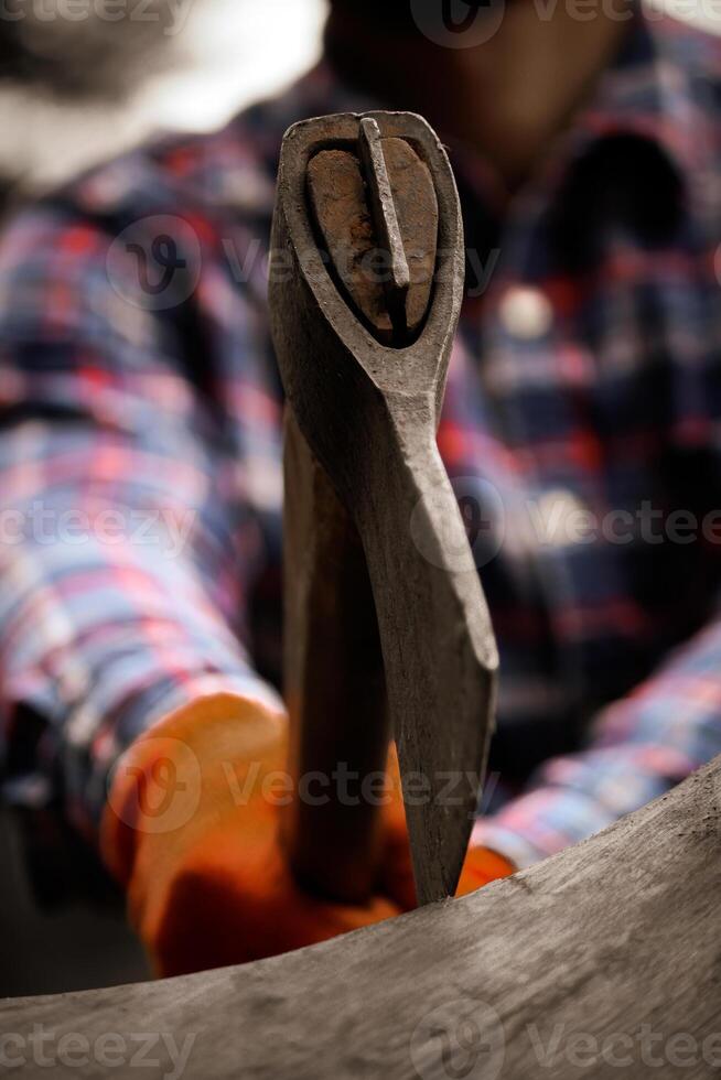 Focused on ax that stuck into wood. Close-Up Of Man Chopping Wood With Axe Outdoors. photo