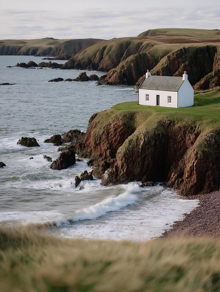 Secluded Coastal Cottage on a Dramatic Cliffside. A tranquil scene of a white house perched atop rugged cliffs overlooking a churning ocean. photo