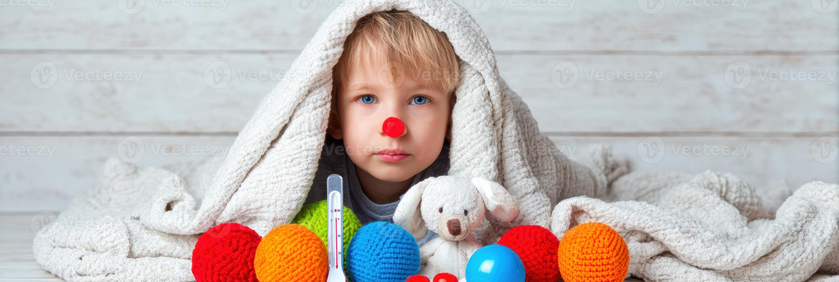 Child With Red Nose Sits Under Cozy Blanket With Toys and Thermometer, Looking Playful and Cheerful in a Bright Indoor Space photo