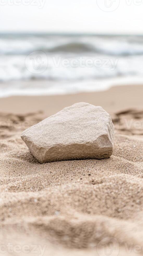 Textured rock resting on golden sand, with gentle ocean waves in the background, evoking a serene coastal landscape. A tranquil beach scene. photo
