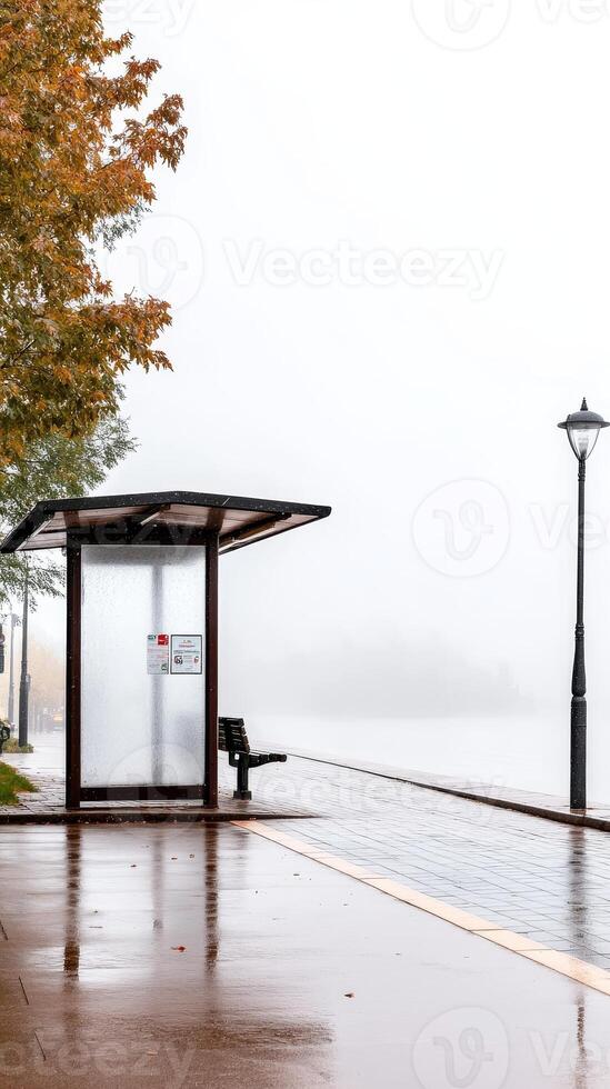 Misty Autumn Morning at an Empty Urban Bus Stop Wet Pavement Reflects Gloomy Sky and Golden Leaves, Awaiting Public Transport photo