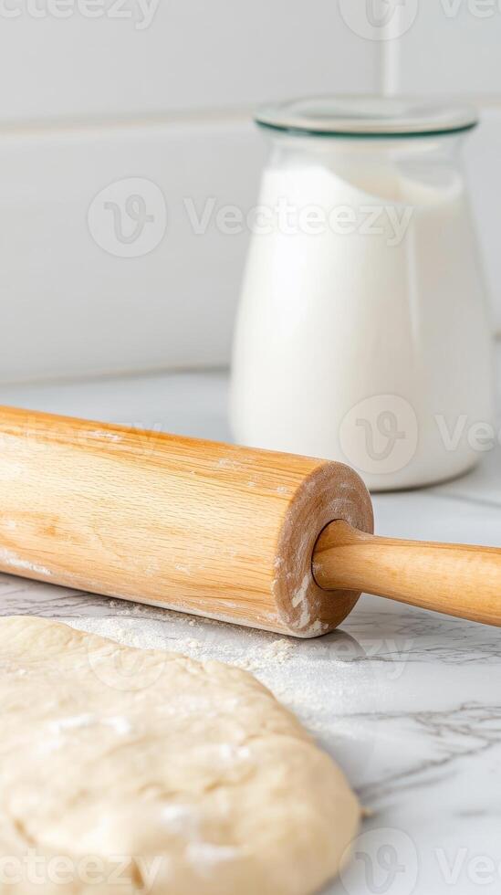 Close-up of a wooden rolling pin and fresh dough on a marble surface, with a jar of milk, perfect for homemade baking creations. photo