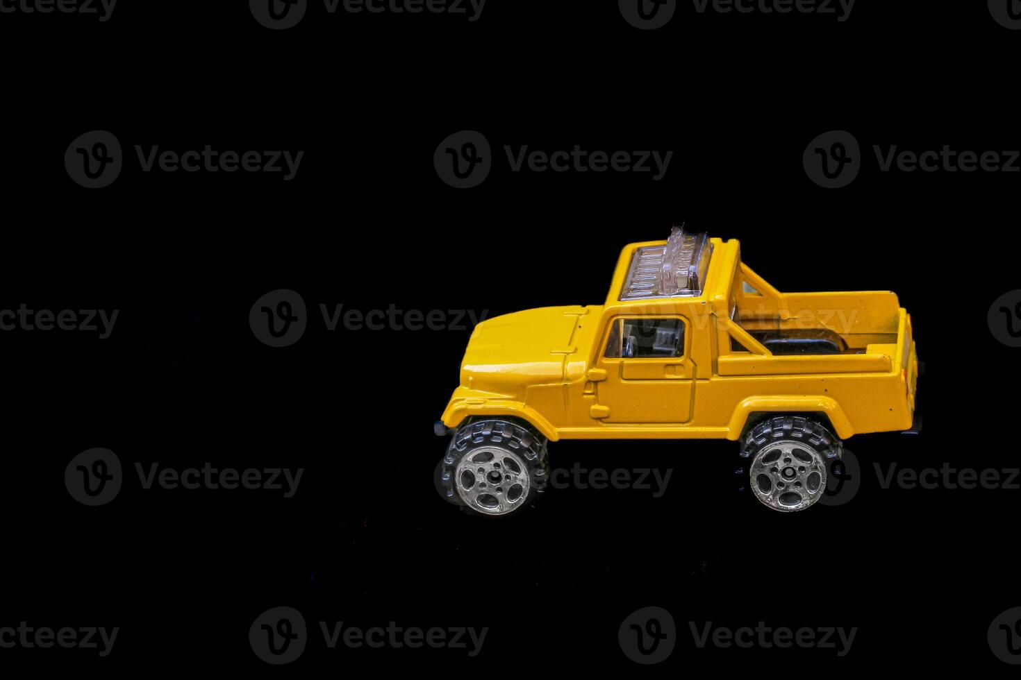 A horizontal photo of a small yellow 4x4 truck model placed on a plain black background. The vehicle sits on the right, leaving space for text or design elements on the left.
