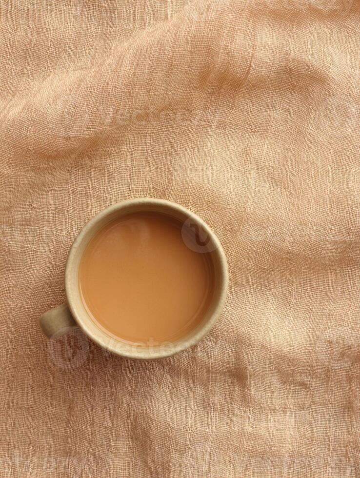 Warm beverage on textured linen fabric in soft caramel tone. Top view for cozy design photo