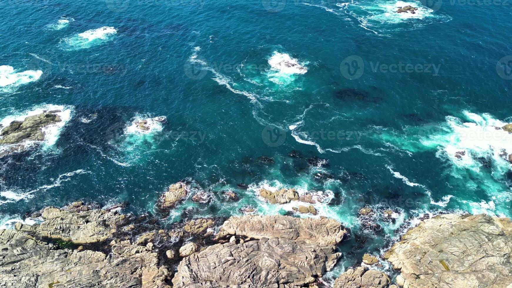A breathtaking aerial view that beautifully showcases the vibrant ocean waves crashing against rugged rocks photo