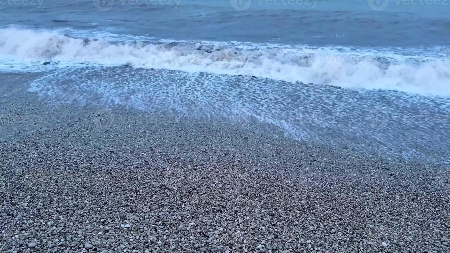 Gorgeous waves gently rolling onto a picturesque pebble beach, beautifully capturing the essence of nature at dusk photo