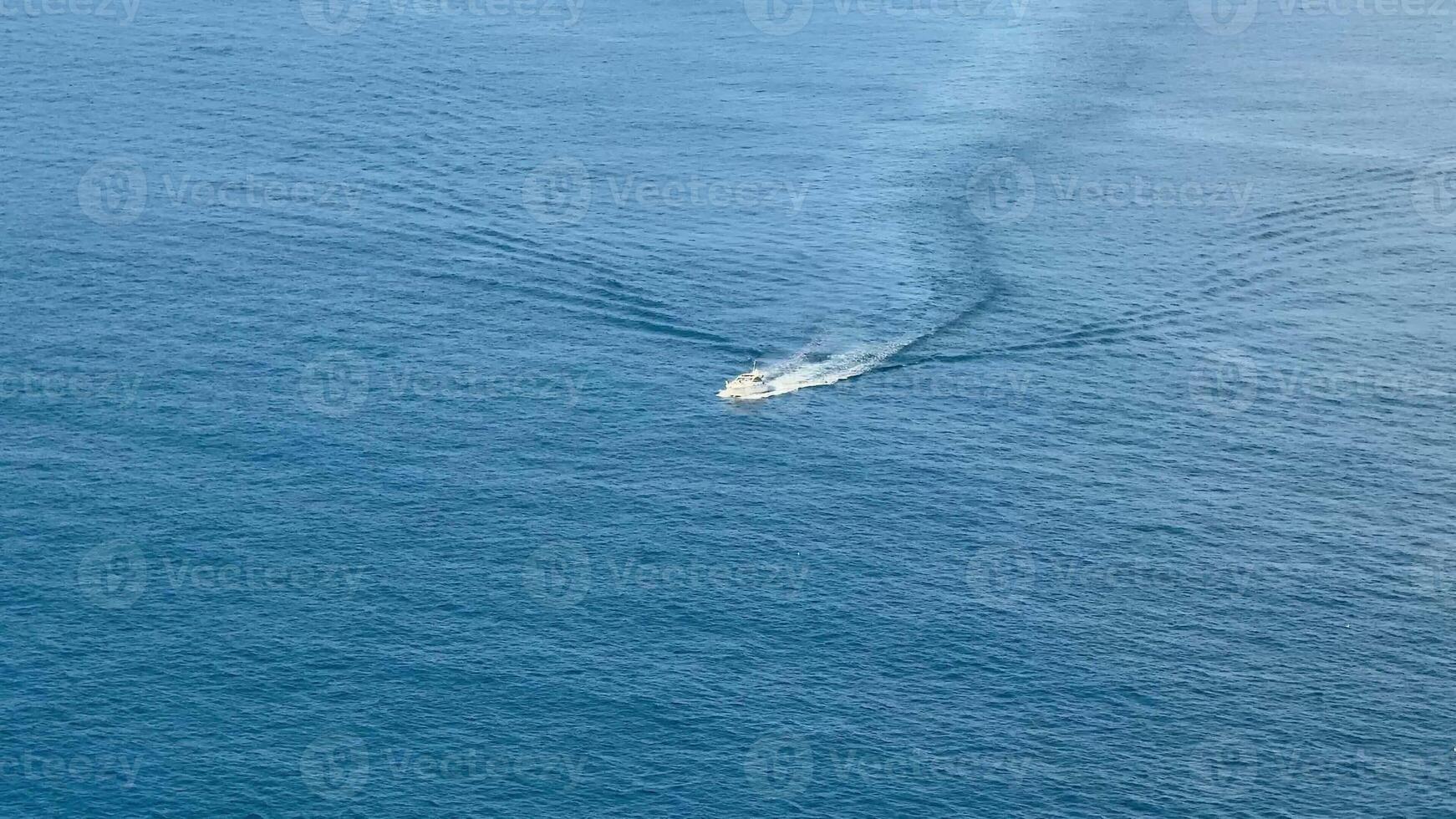 An aerial shot capturing a boat's wake on serene blue waters, showcasing marine serenity and adventure. photo