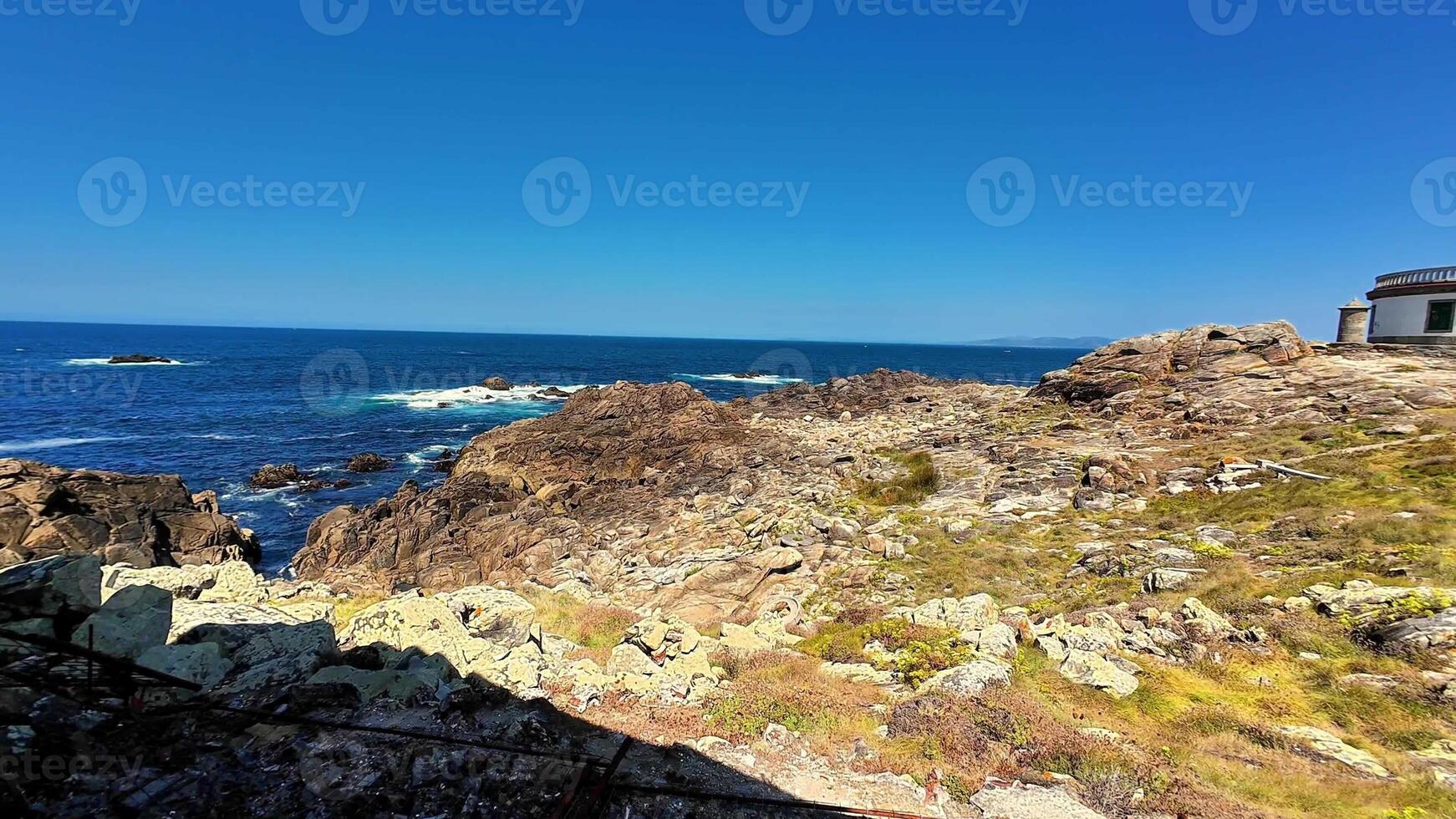 A breathtaking coastal landscape featuring rugged, jagged rocks alongside the shimmering blue ocean beneath a clear sky photo
