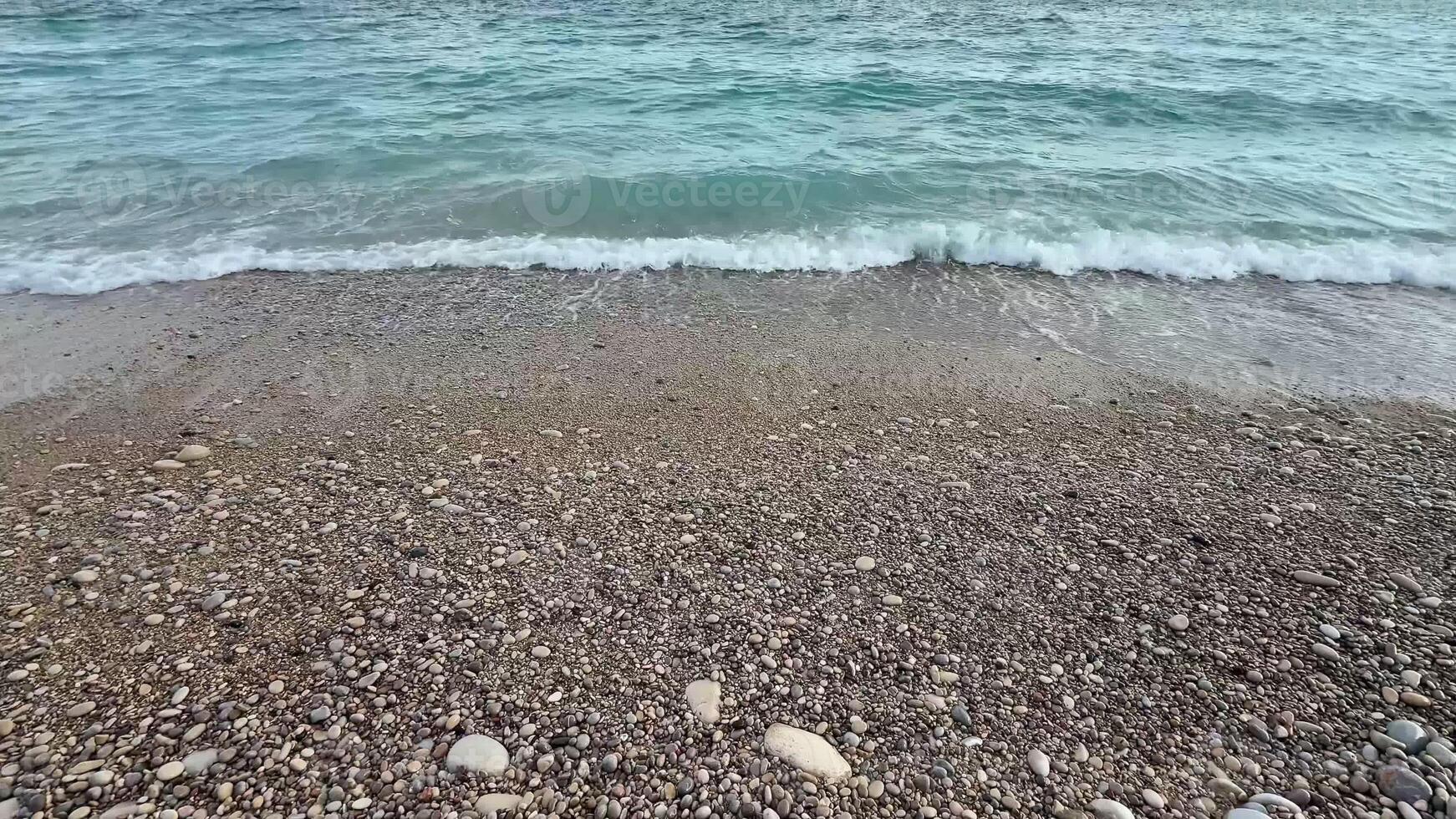 A beautifully calm beach scene that showcases the soft waves gently lapping against a pebblestrewn shore photo