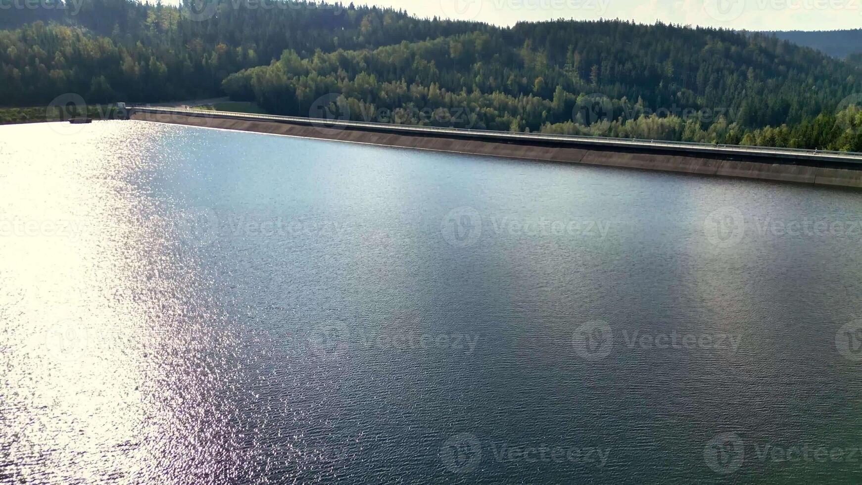 A beautifully serene lake scene, reflecting golden sunlight with a stunning backdrop of dense photo