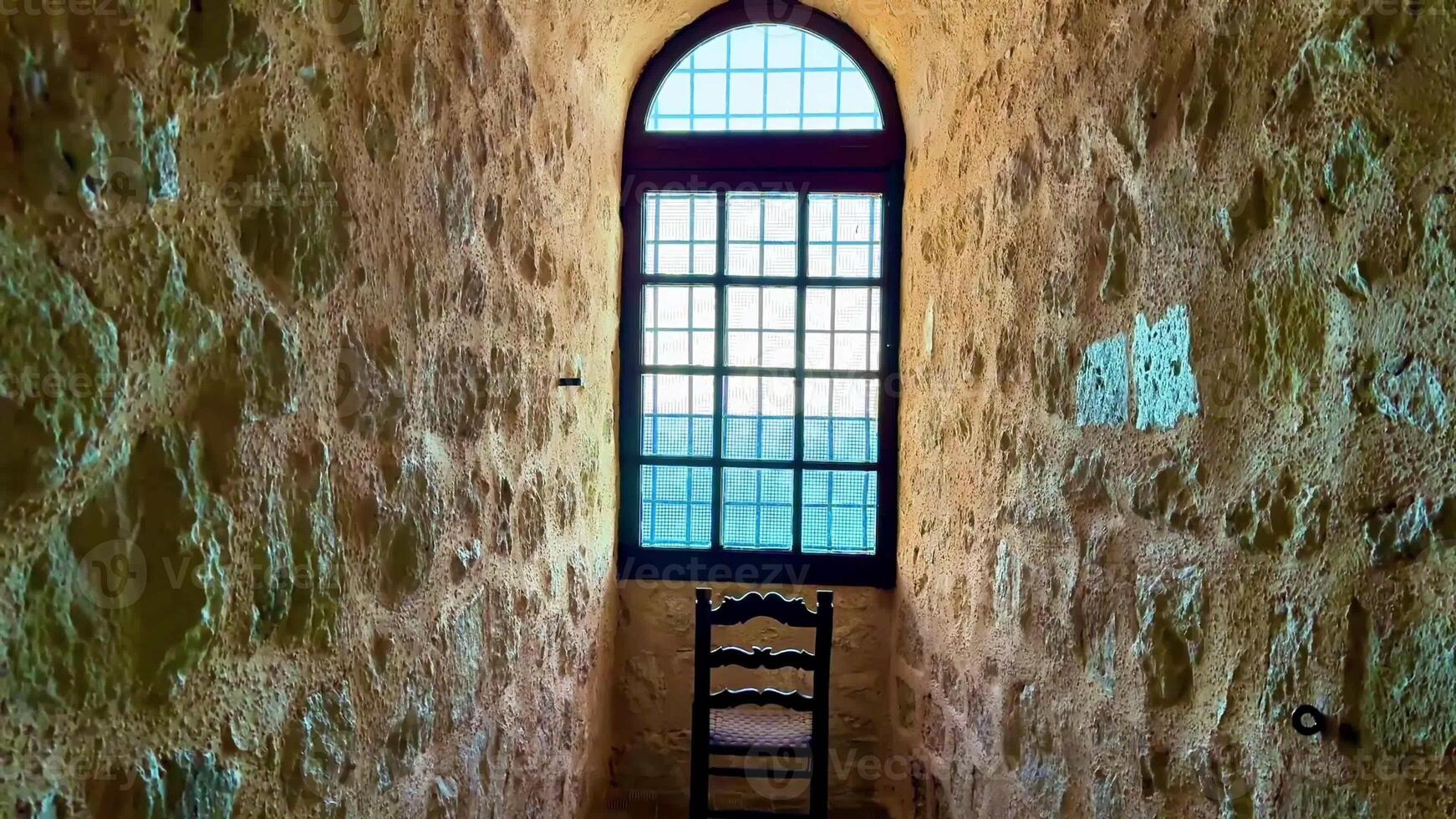 A serene stone corridor featuring a charming window and a simple chair, ideal for atmospheric visuals. photo