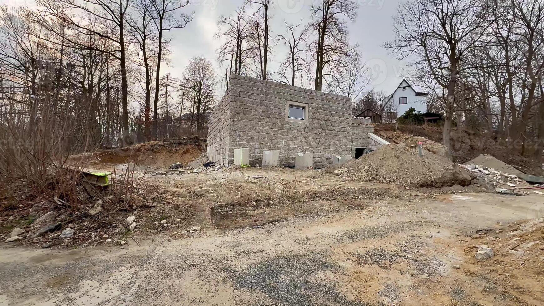 An incomplete building is situated in a lush area surrounded by trees and scattered construction debris photo
