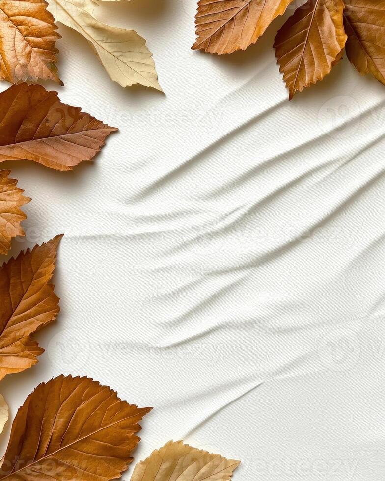 Autumn leaves scattered on textured white fabric background photo
