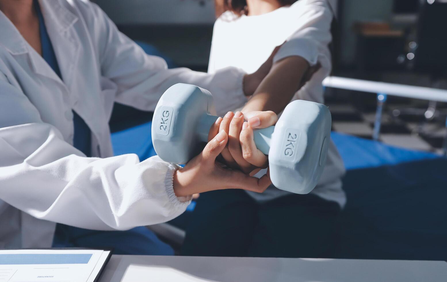A woman is holding a dumbbell while a doctor is helping her photo