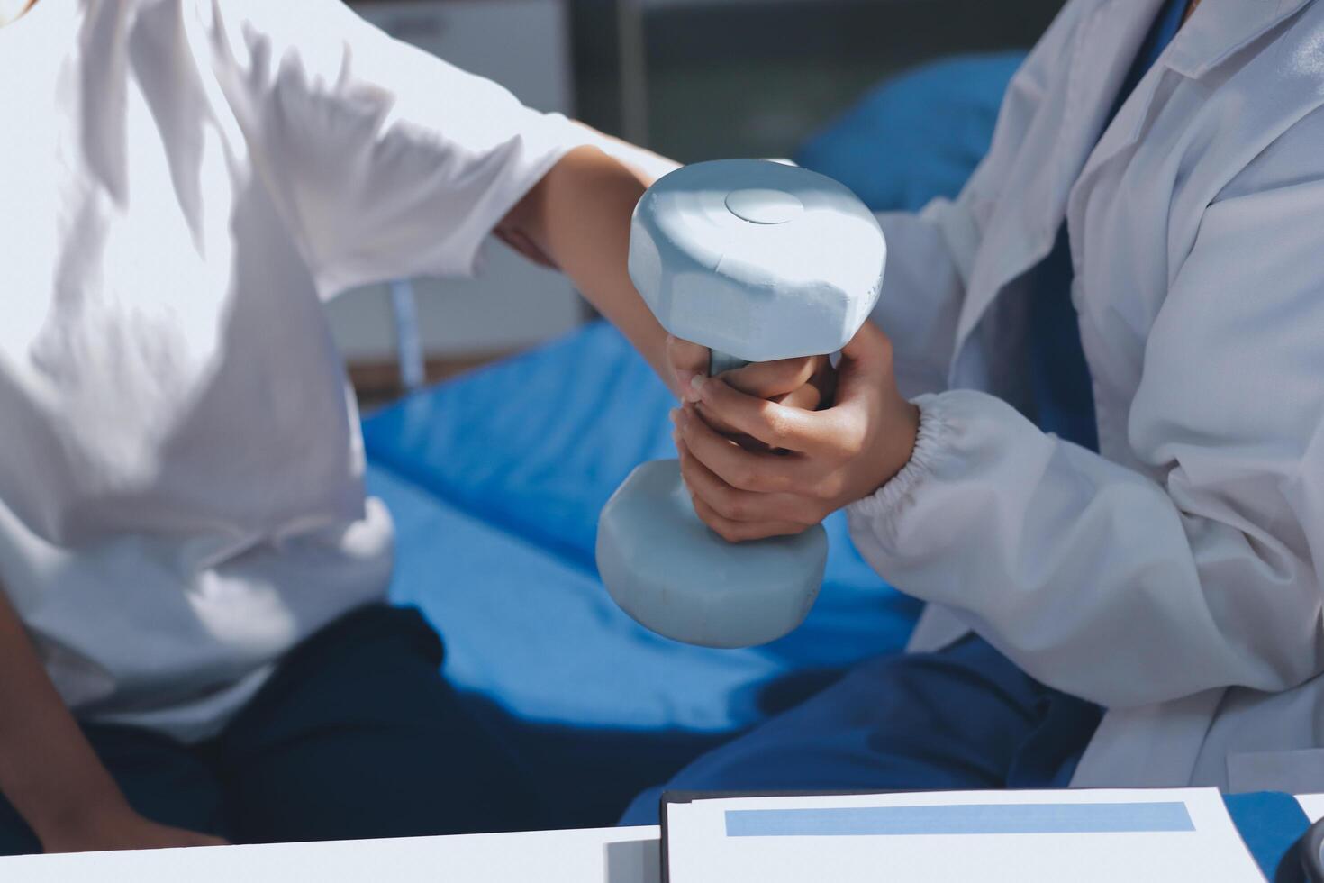 A doctor is holding a dumbbell while another person is sitting on a bed photo