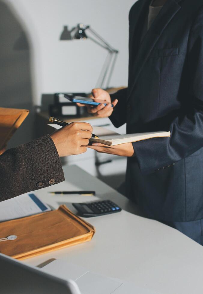 A man in a suit is signing papers while a woman is holding a clipboard photo