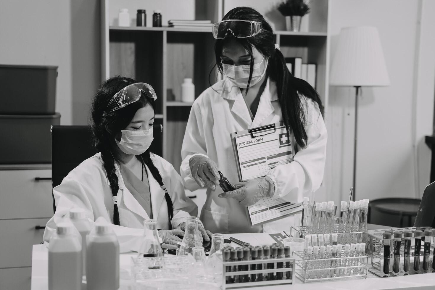 Two women in lab coats working on something photo