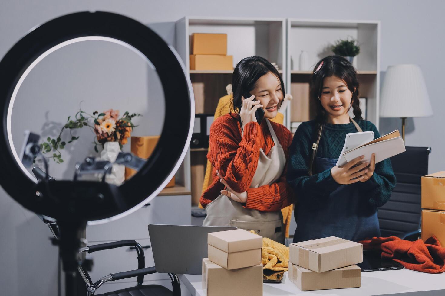 Two women standing in front of a camera and holding boxes photo
