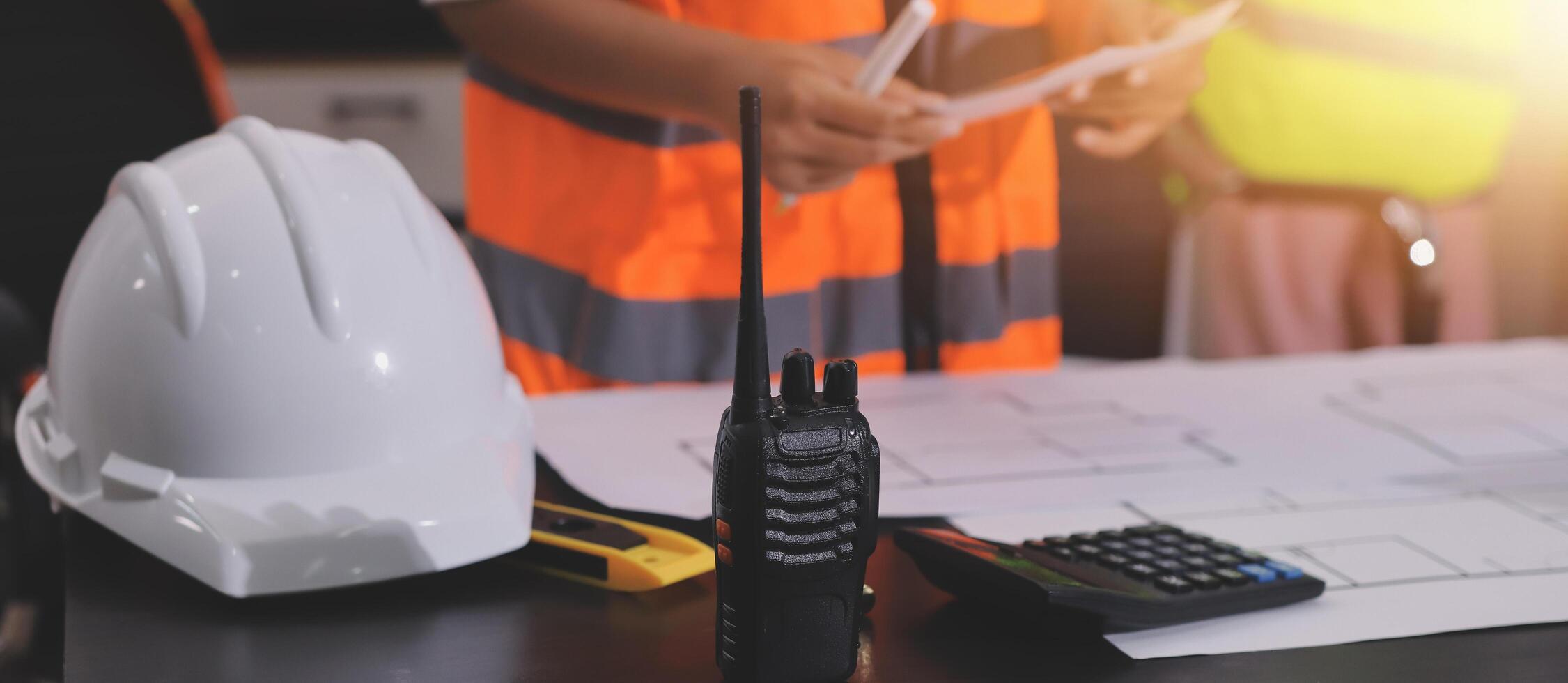 A construction worker is holding a radio and a hard hat photo