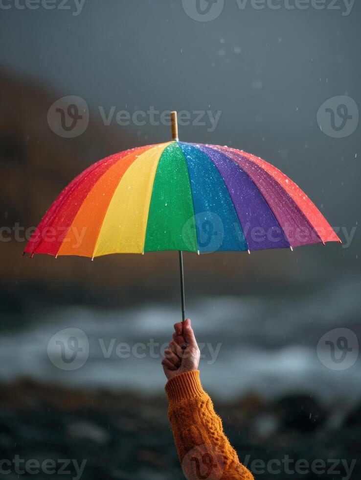 Hand Holding a Rainbow Umbrella in a Storm, Symbolizing Hope and Support in Challenging Weather Conditions photo