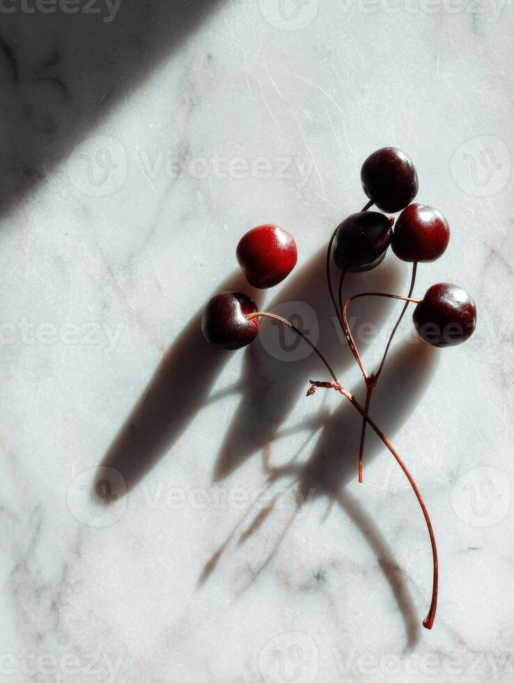Close-up View of Cherry Stems Casting Shadows on a Marble Surface in a Minimalist Setting With an Empty Upper Third Space photo
