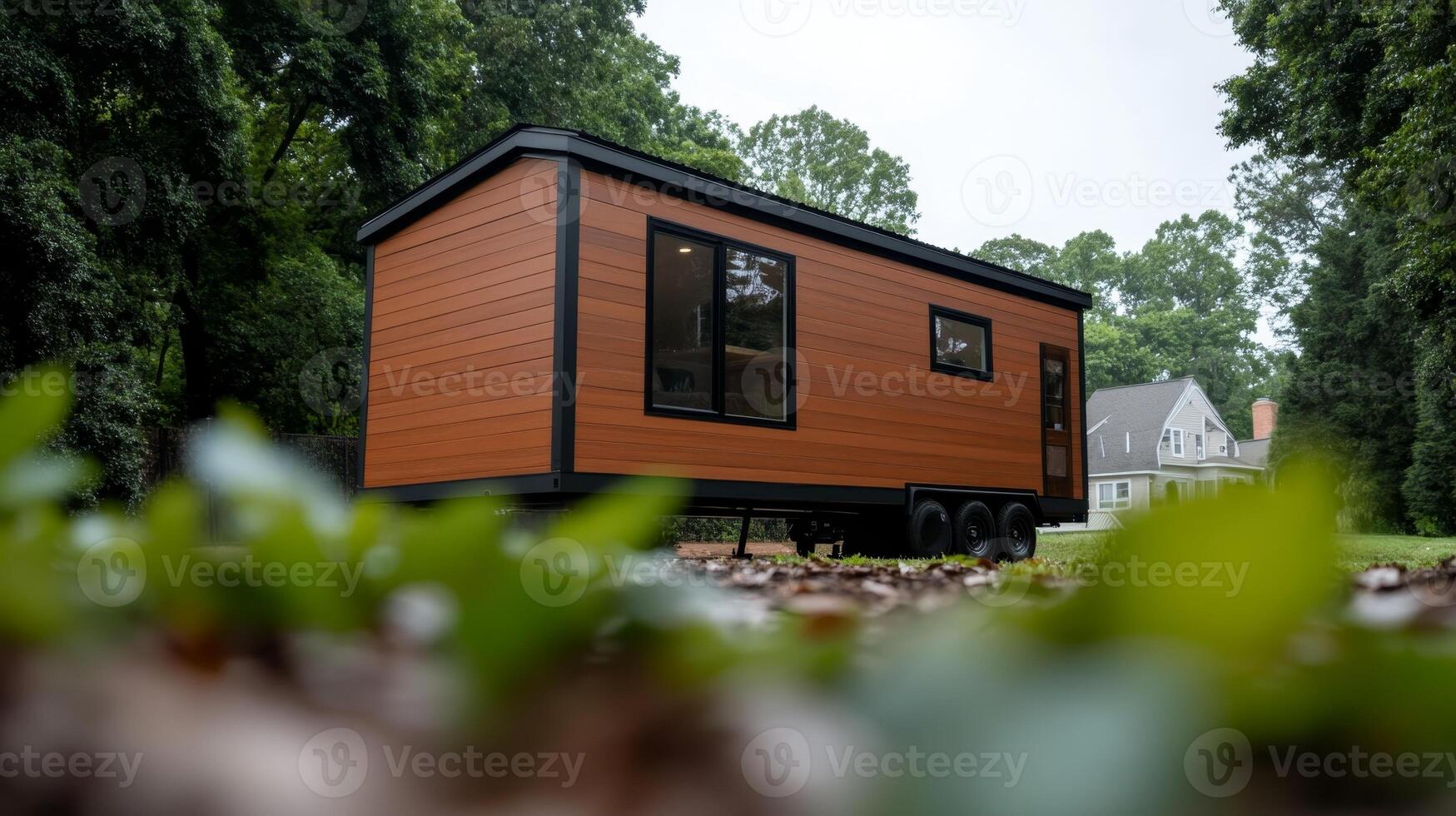 Modern tiny house on wheels surrounded by greenery in a residential area photo