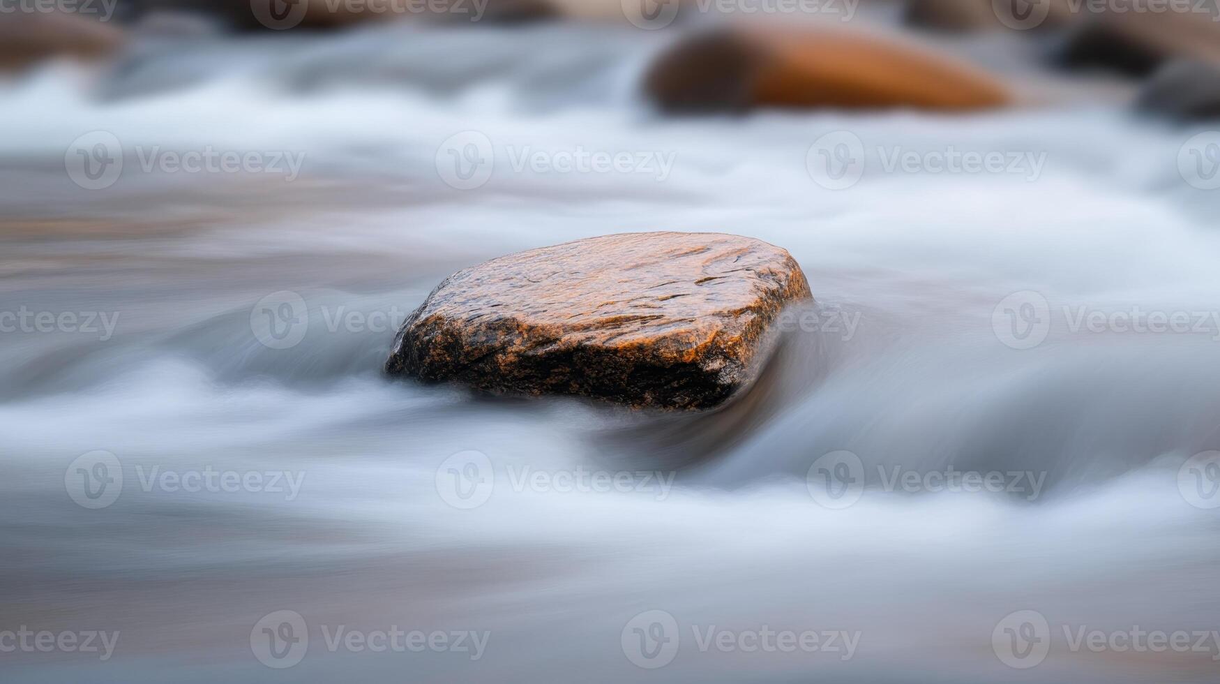 Water flows over smooth stones in a tranquil river setting during sunrise creating a serene nature scene photo
