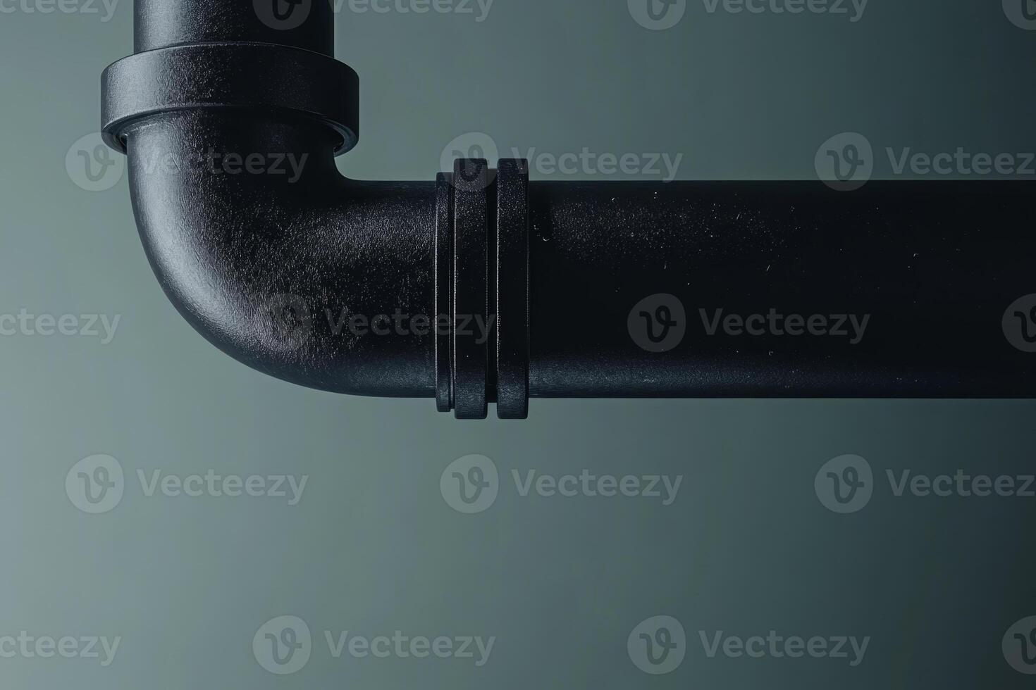 Black plastic plumbing pipe fitting against a dark background highlighting curves and angles of the plumbing design photo