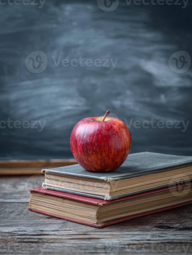Desk With Apple and Stacked Books Beside Chalkboard in Classroom Setting photo