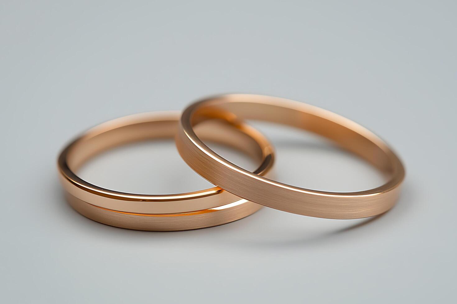 Close-up of Intertwined Rose Gold Wedding Bands on Gray Background. A sophisticated image perfect for wedding announcements, jewelry websites, or romantic concepts. photo