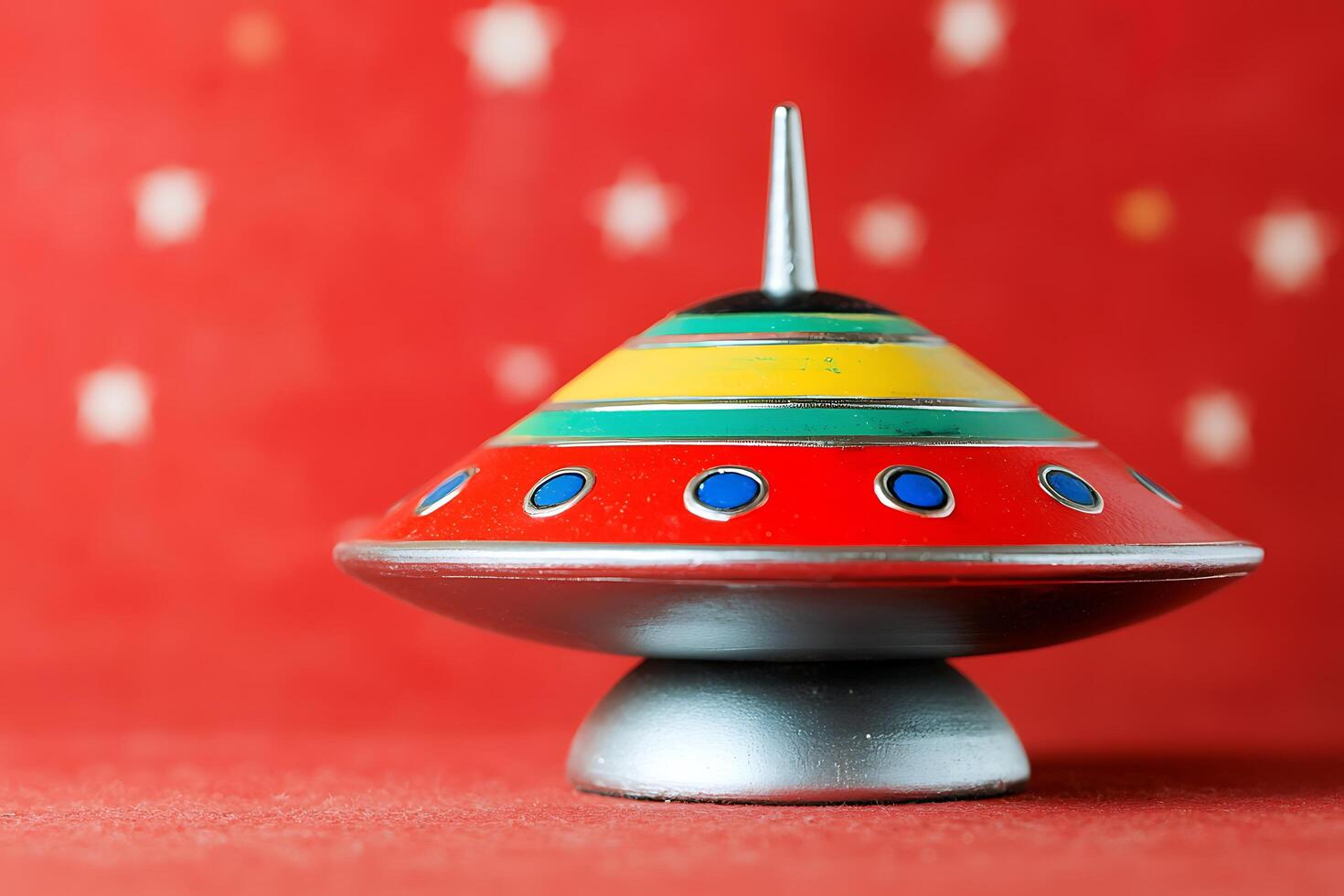 Retro Flying Saucer Top Toy on Red Background. A colorful spinning top shaped like a vintage UFO. photo