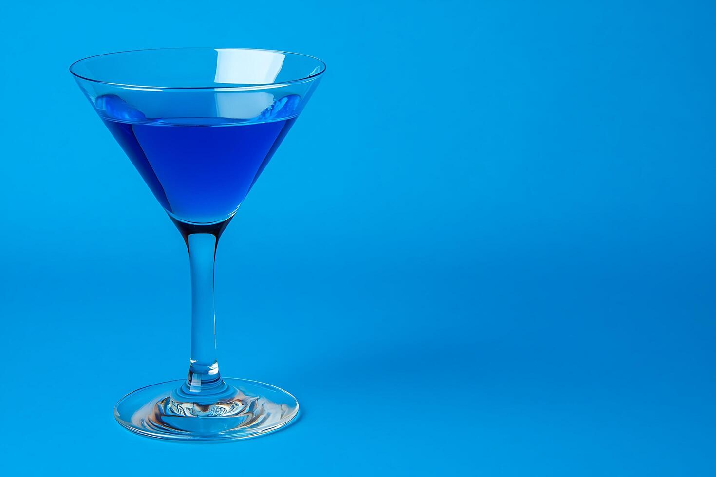 A Glass of Vibrant Blue Cocktail on a Blue Background. A stylish image perfect for beverage-related projects and designs. photo