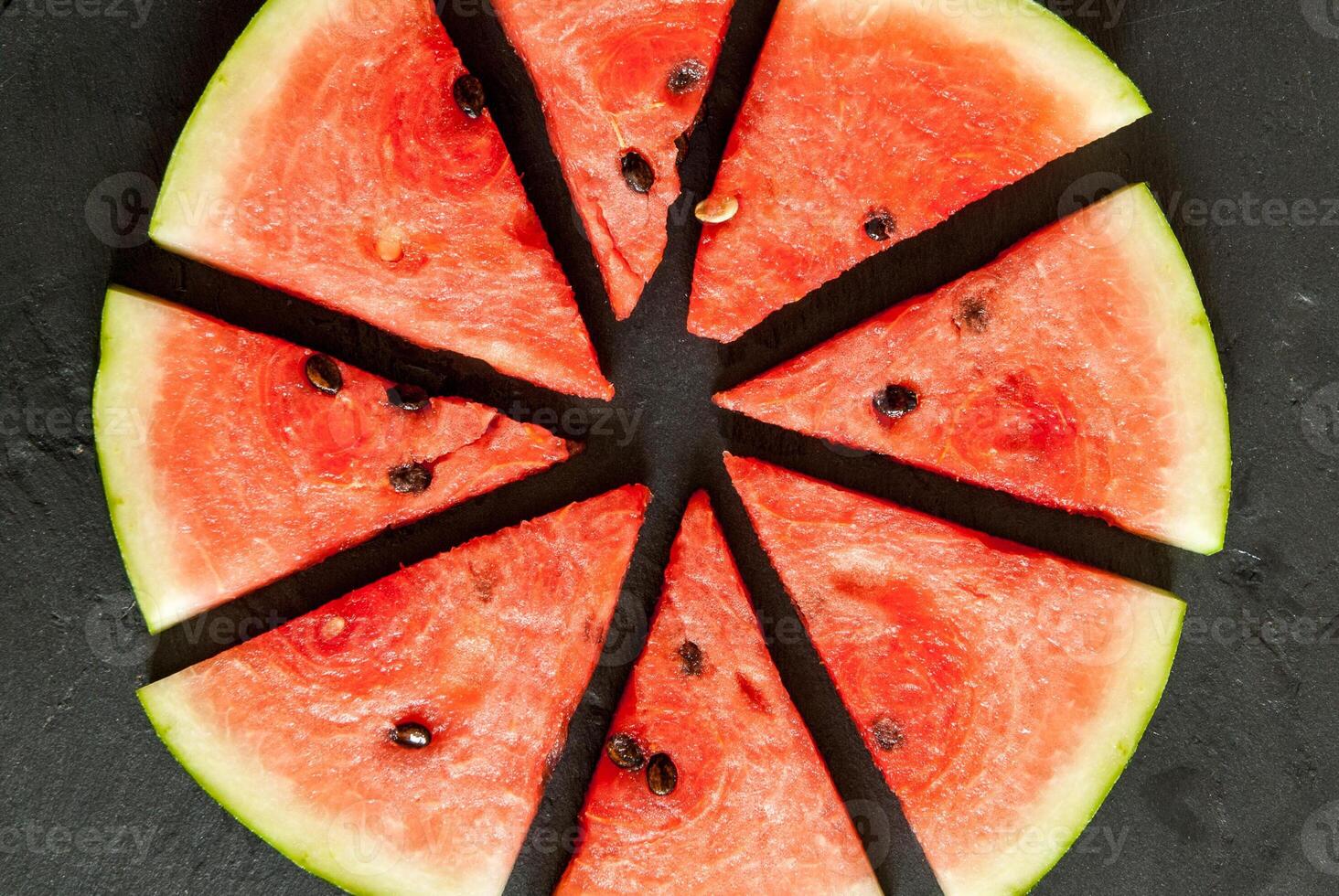 Watermelon slices cut into slices on a black slate photo