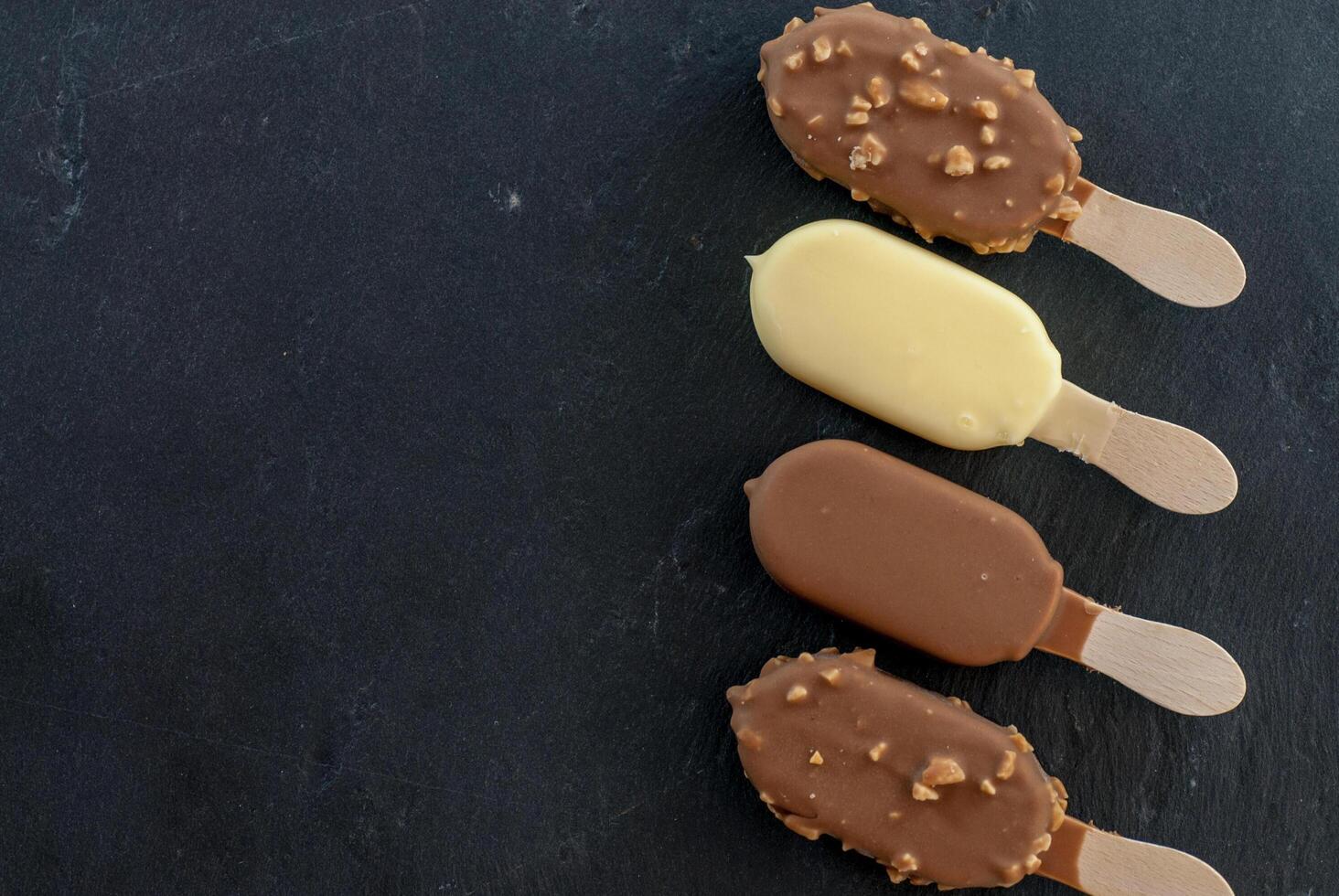 assorted mini ice creams on stick on black photo