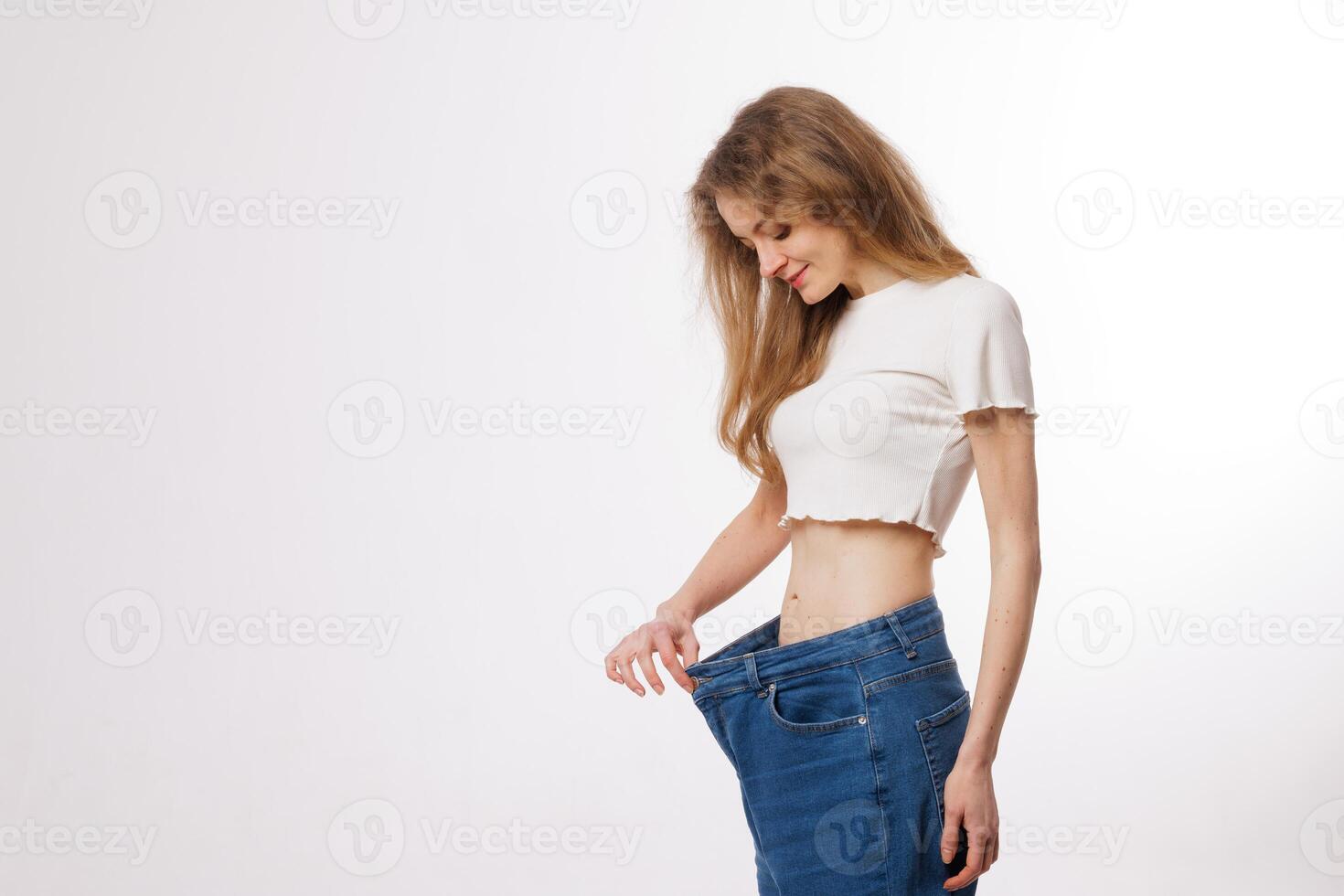 Woman Shows Weight Loss Success with Loose Jeans After Diet and Healthy Lifestyle Transformation photo