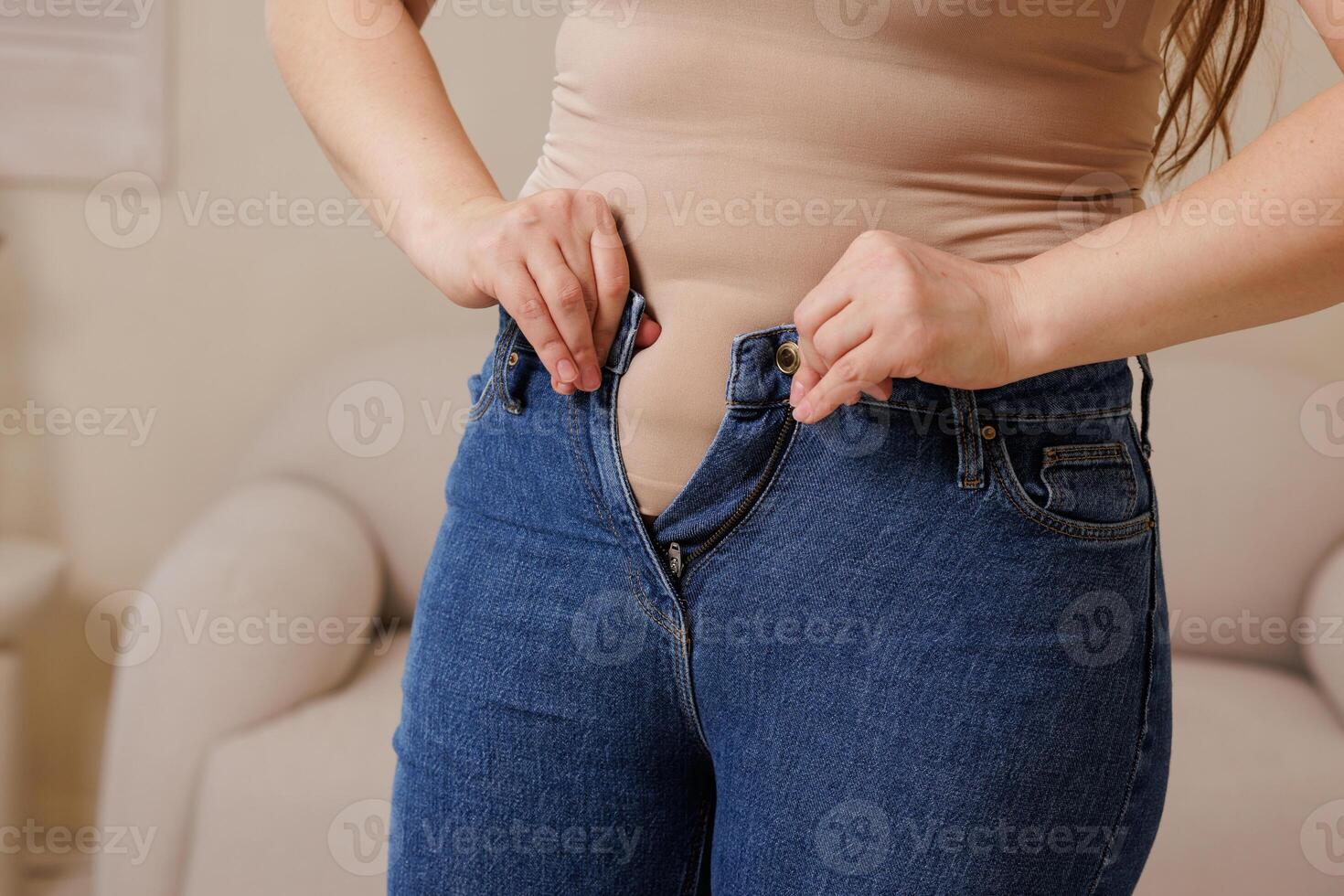 Close Up of Woman Struggling to Button Tight Jeans Weight Loss Diet Body Image and Motivation Concept photo