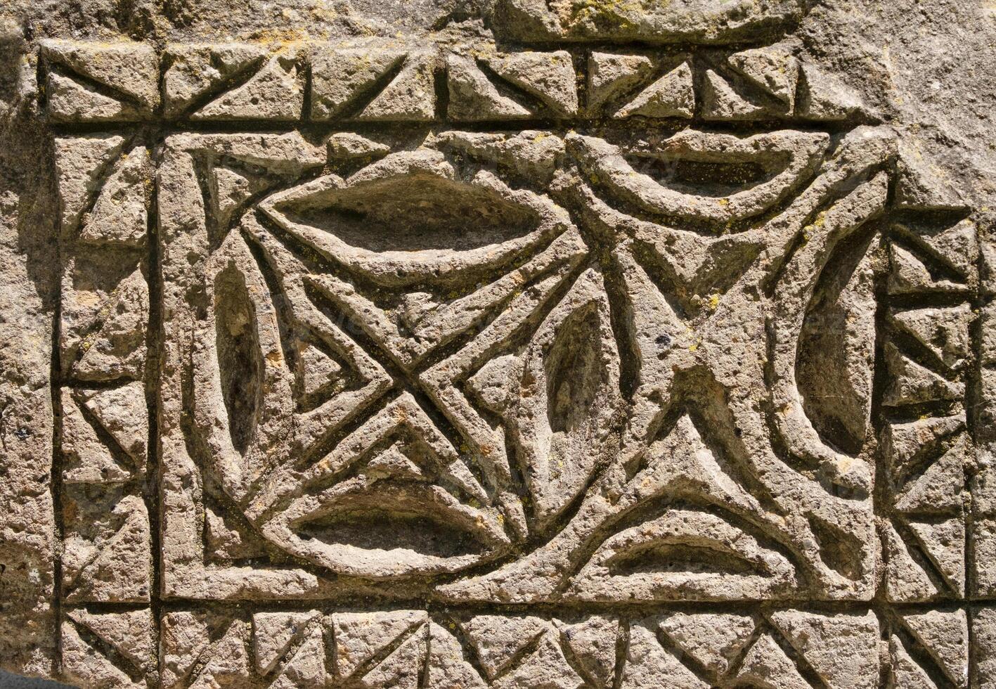 fragment of a pattern carved into stone, textured background photo