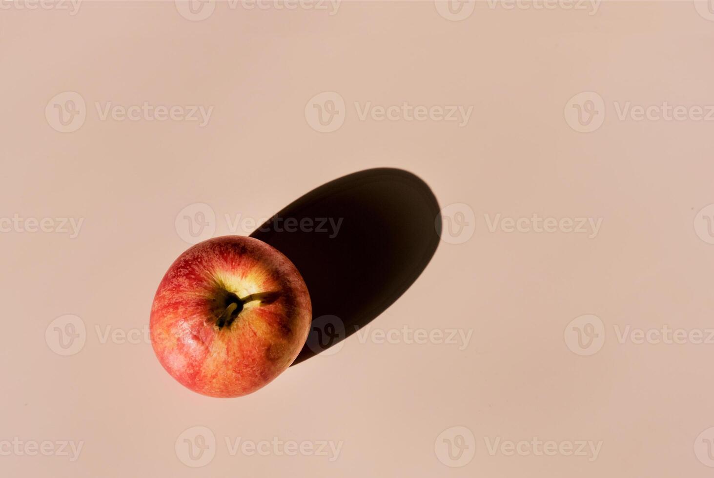 one red apple on beige background, with hard shadow, copy space photo