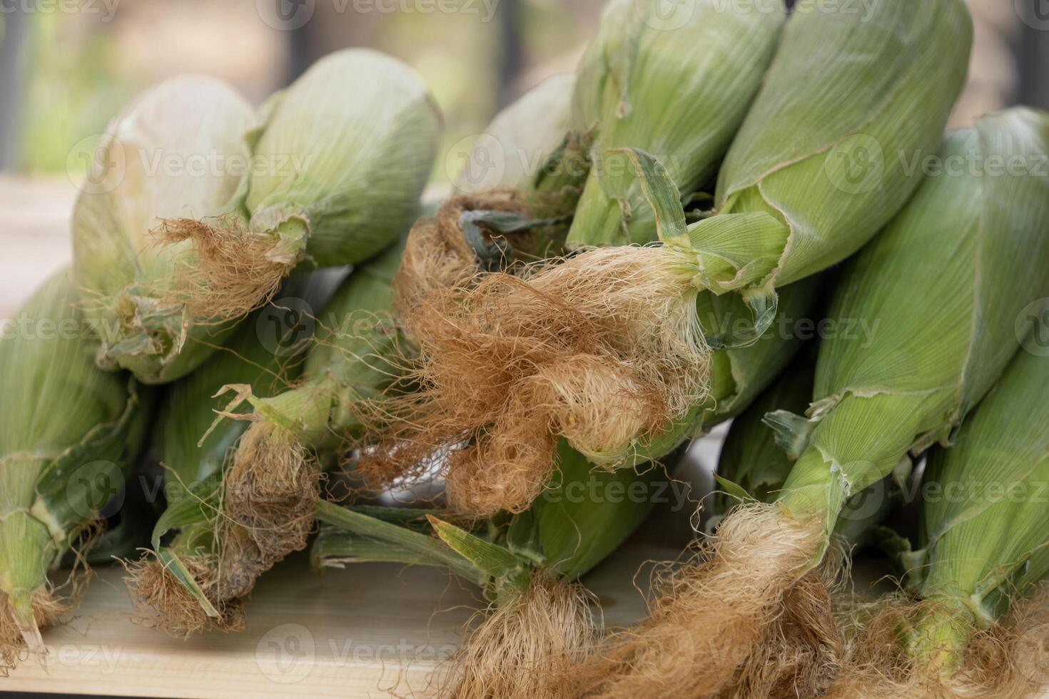 Green corn cobs lying on a counter at a market, close-up photo