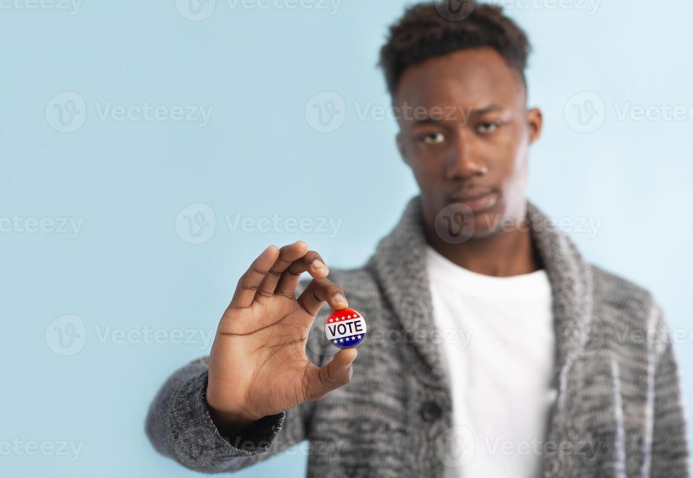 African Citizen of America holding Stickers to indicate that I have already fulfilled the duty to vote today in the American elections, blue background, copy space photo
