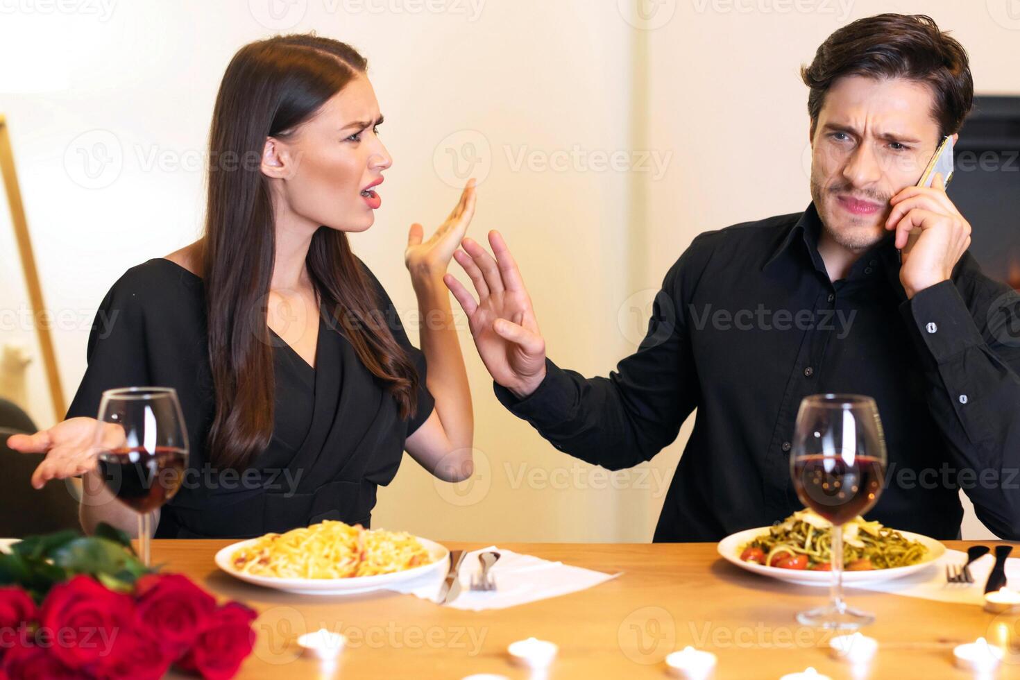 Annoyed angry woman looking and screaming at her man who talking on mobile phone and telling her to shut up and wait while having date in restaurant, quarrel and conflicts in couple concept photo